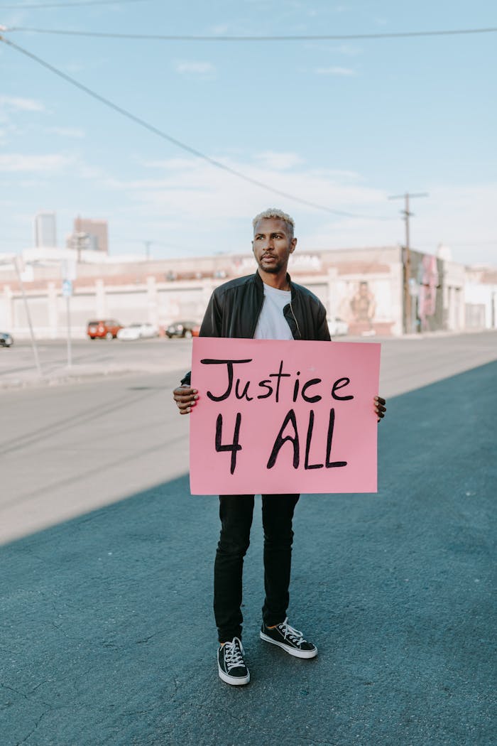 Man Standing on the Street Holding a Poster